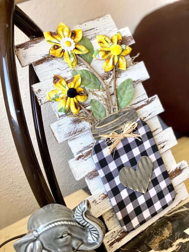 DIY Sunflower decor with yellow fabric sunflowers on wooden chippy paint background coming out of a buffalo check mason jar.