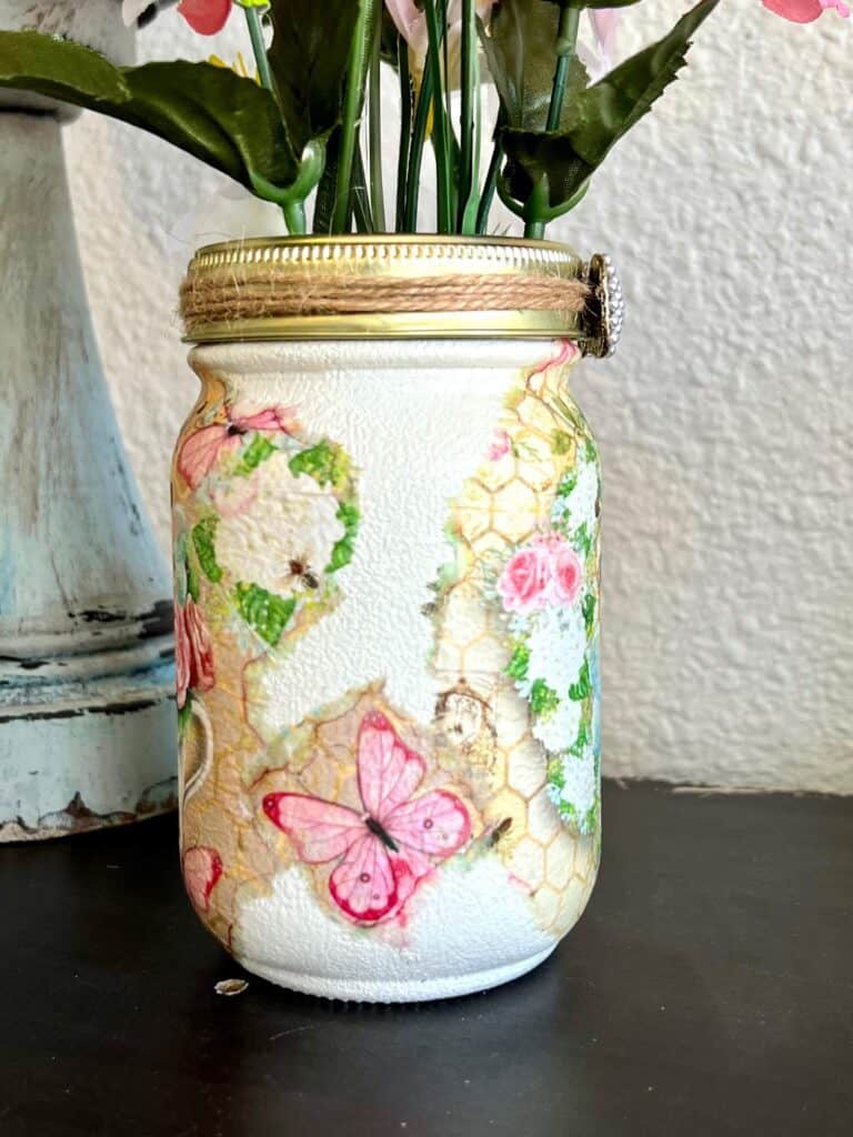 Side of the mason jar with a pink butterfly on tissue paper Mod Podged to it.