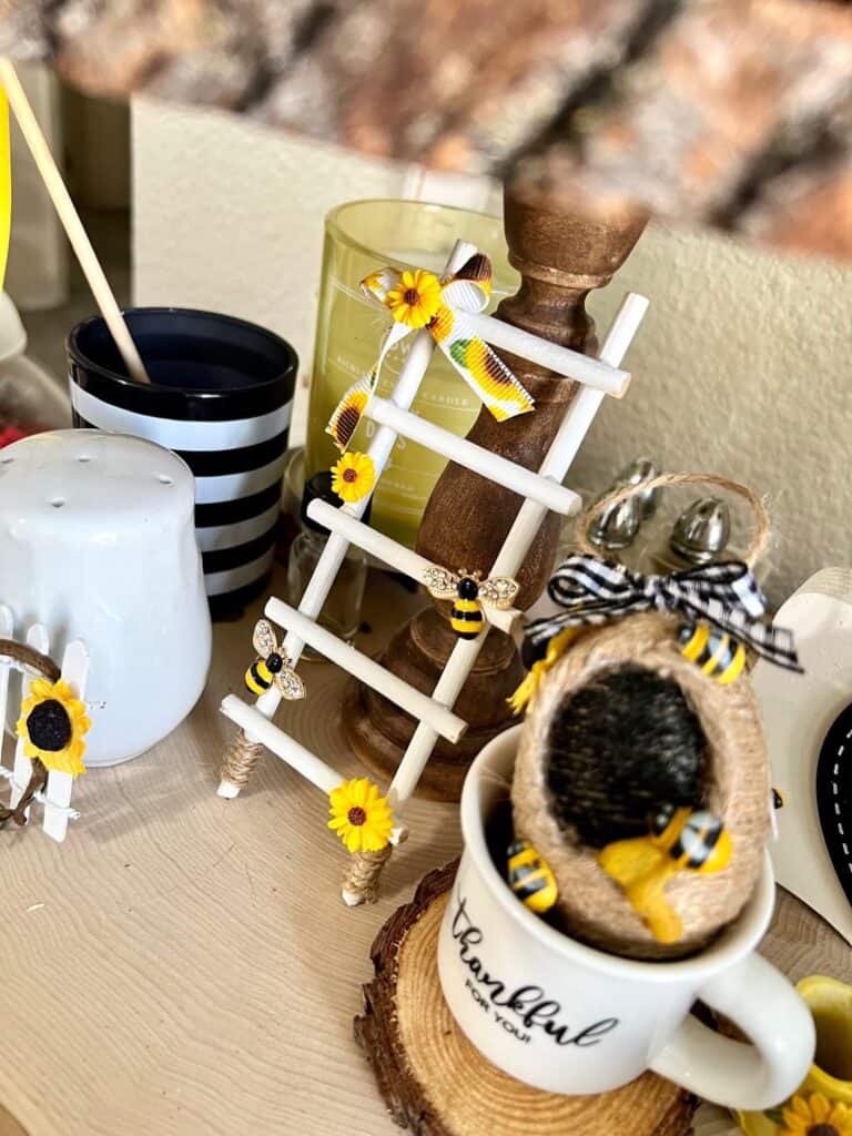 Sunflower and Bee mini Tiered tray decor ladder next to a small twine wrapped beehive in a small thankful mug on a tiered tray.