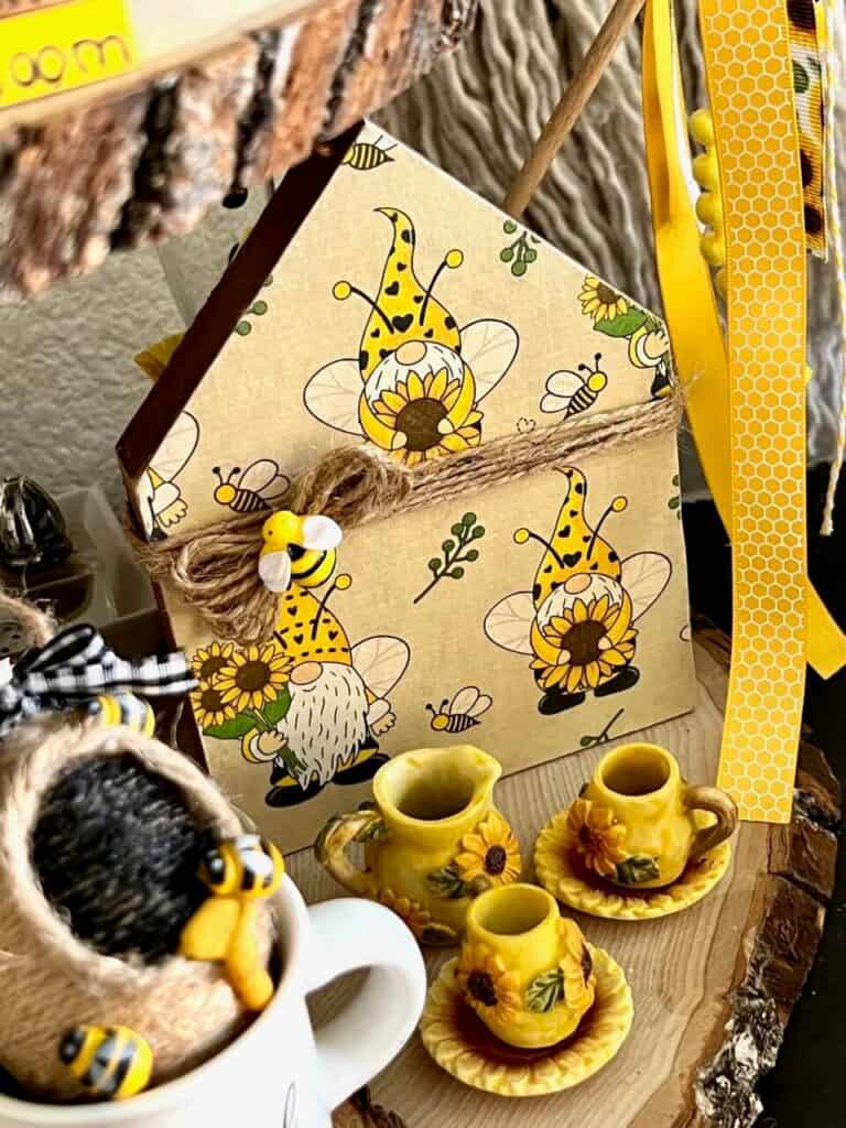 Mini Dollar Tree wooden house with sunflower bee gnome paper mod podged to it and twine wrapped around it to make an easy and cute tiered tray sitter for decor.