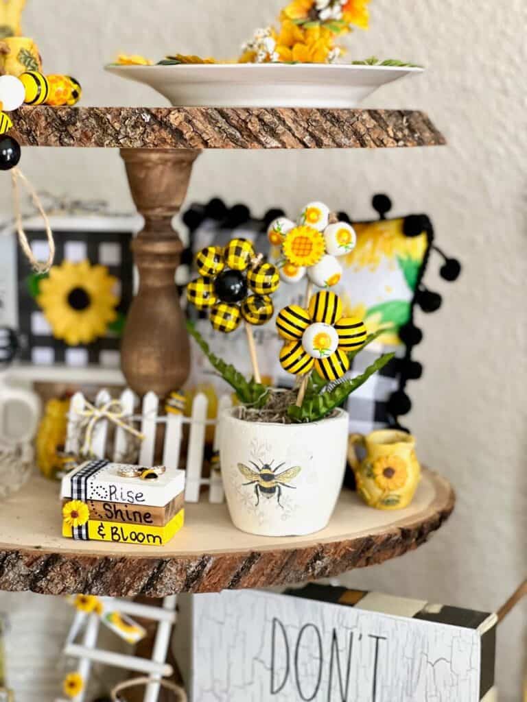 Wood bead flowers on a tiered tray next to a mini bookstack decor.