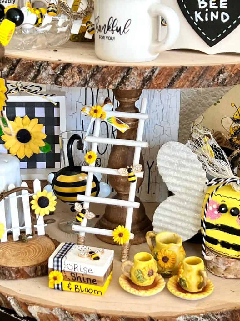 Small white ladder with 5 rungs sitting next to a bunch of other sunflower and bee crafts and decor.