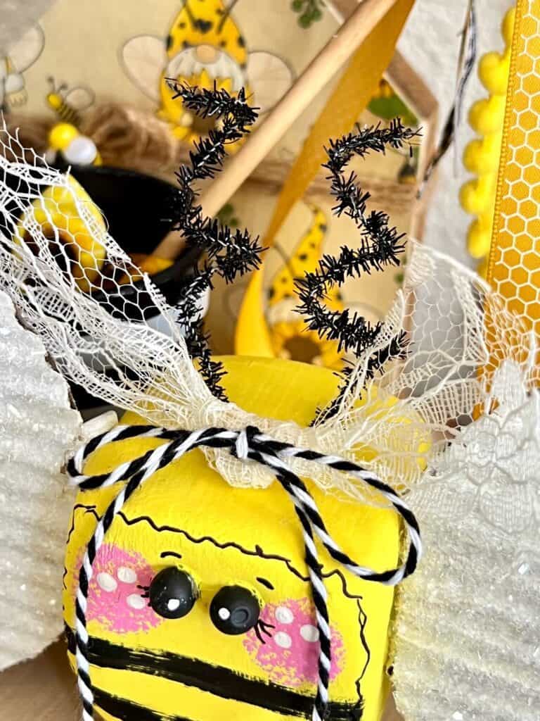 Pipe cleaner bumblebee antennae and a lace and bakers twine bow on top of the bumblebee head 