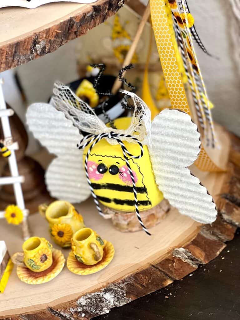 DIY Dollar Tree foam dice bumblebee made with cardboard wings with diamond dust a whimsy painted face and a lace and bakers twine bow.