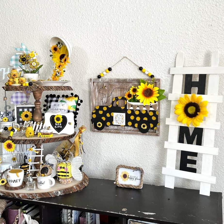 Sunflower and Bee decorated rustic wooden 3 tiered tray next to a yellow polka dot sunflower truck next to the DIY Paint stick HOME ladder decor.