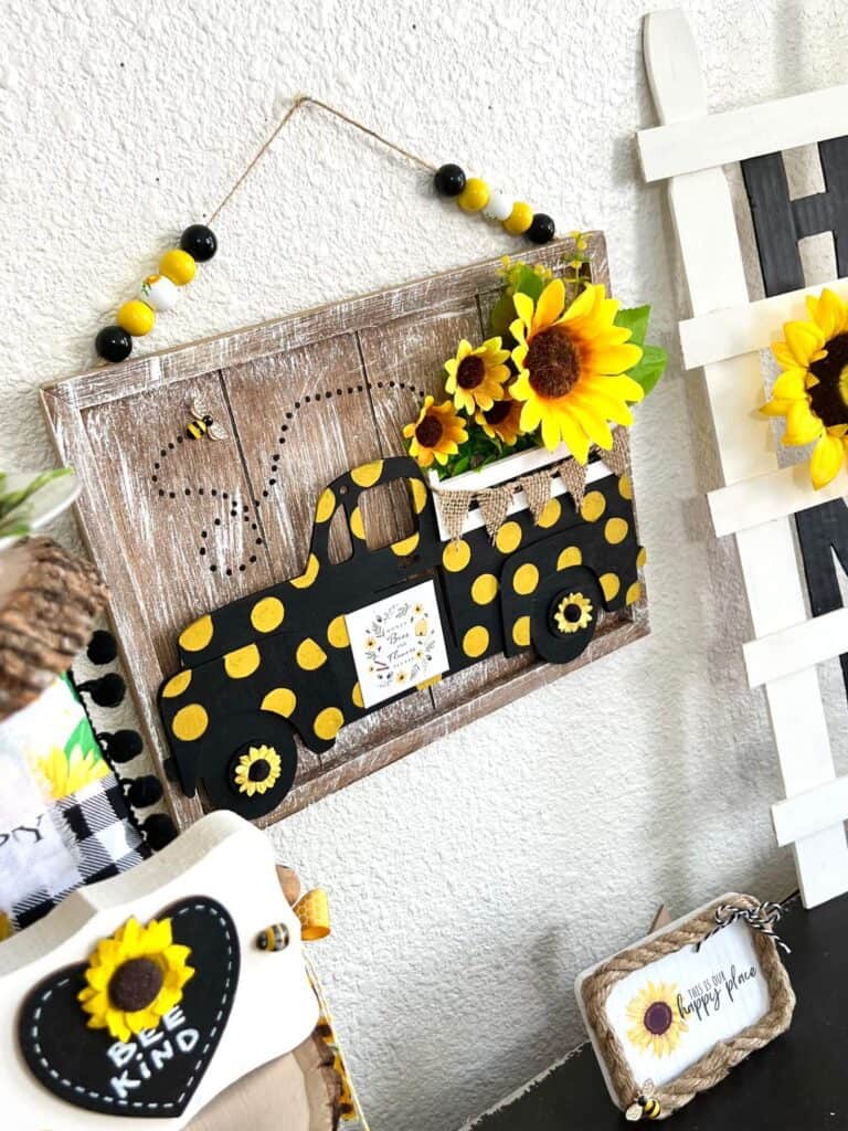 DIY Dollar Tree Sunflower Truck made with Dollar Tree supplies, faux sunflowers, a honey bee, wood bead hanger, and black with yellow polka dots for spring and summer DIY affordable decor.