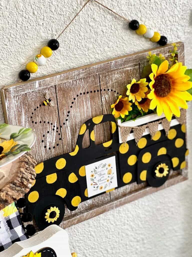 Close up of the dollar tree sunflower truck with yellow polka dots, sunflowers in the truck bed and a bumblebee flying out of the truck bed.