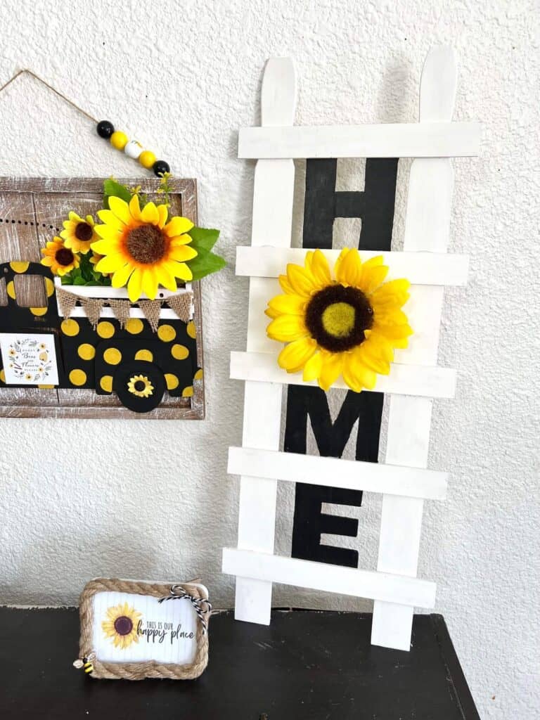 DIY Paint Stick Decor Ladder with the word HOME and a sunflower "O" for easy and affordable way to decorate your home on a budget.