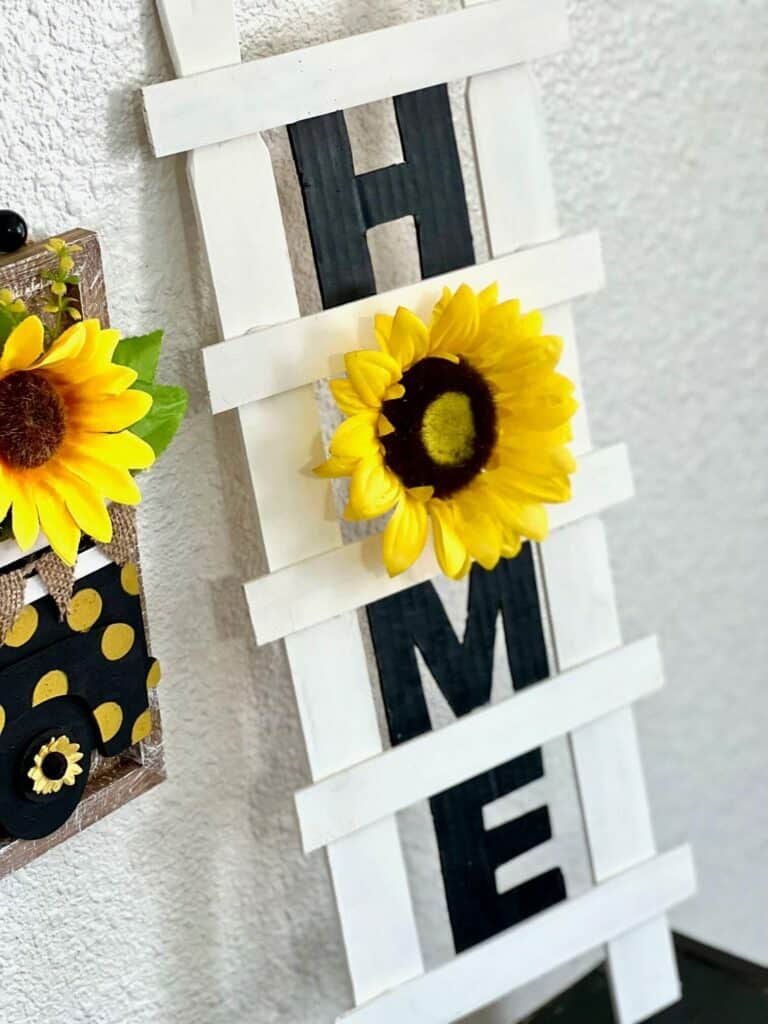 DIY Paint Stick Decor Ladder with the word HOME and a sunflower "O" for easy and affordable way to decorate your home on a budget. 