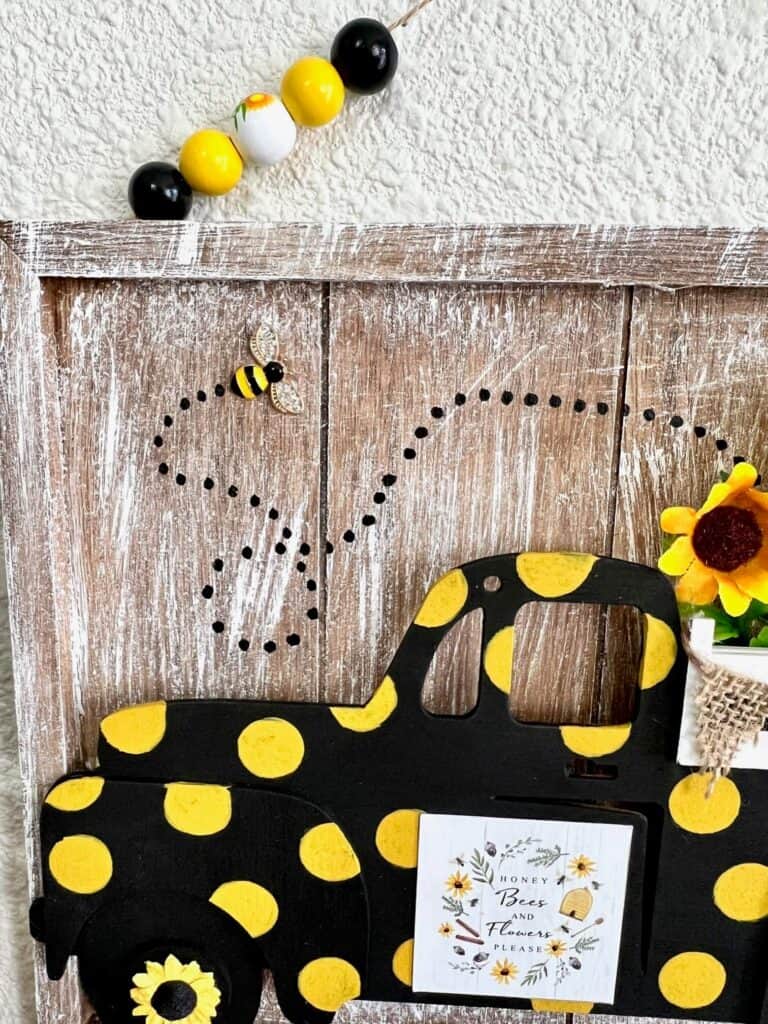 A rhinestone bee embellishment coming out of the sunflower truck bed with a dotted black line to show the trail that the bee flew.
