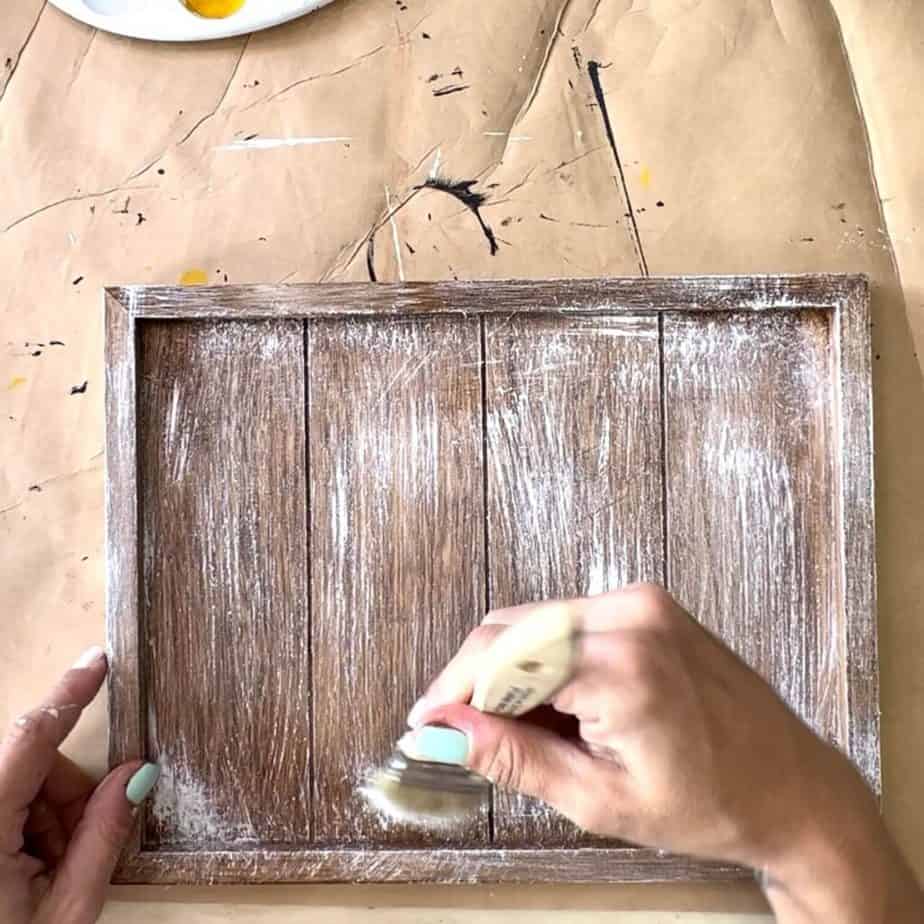 Take a chip brush and dry brush white paint over the top of the wooden frame.