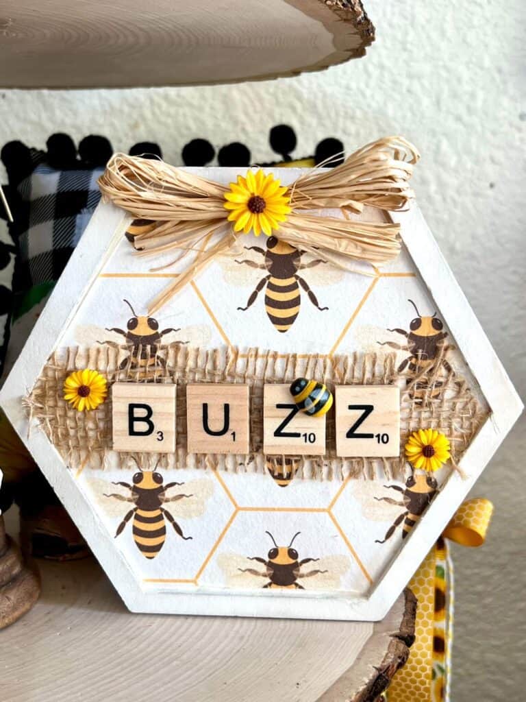 Buzz Honeycomb decor with scrabble tile letters and a small raffia bow with sunflower at the top.