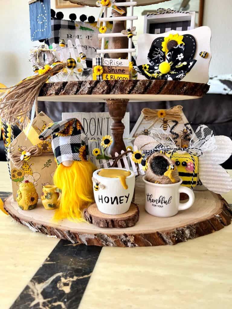Bottom tier of the rustic tray showing the mini honey pot, bee hive, sunflower gnome, gnome house sitter, and the 2 pieces in the back of the tray that you can't see well.