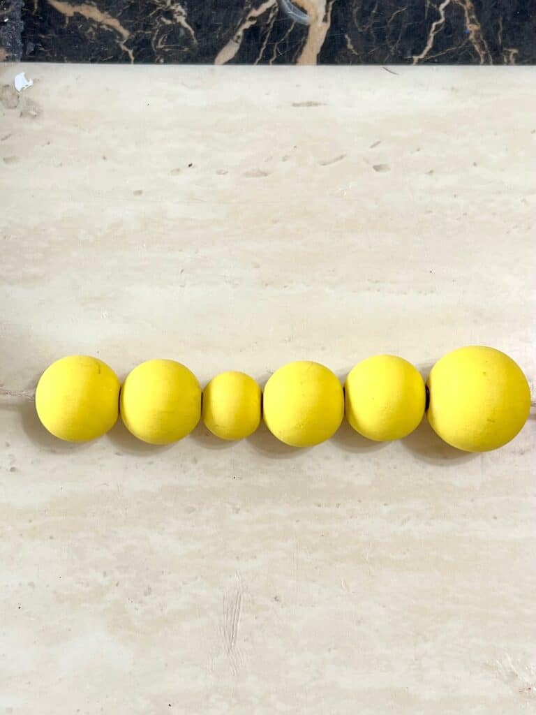 5 yellow beads on a garland in a particular order to show the pattern of sized beads.