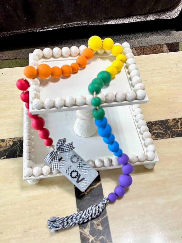 DIY Rainbow Wood Bead Garland on a rectangular 2 tiered tray as decoration for pride month.