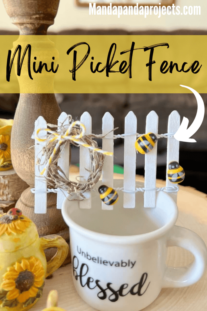 Small white picket fence decor with a mini wreath and yellow bow and small bumblebees, sitting on top of a mini mug that says "unbelievably blessed".