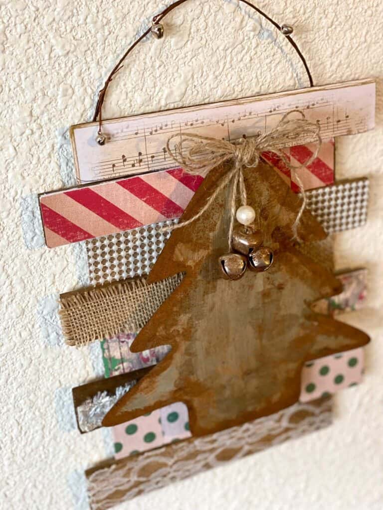 Portrait view of the left side of the faux rusted vintage tree showing the wooden shims with scrapbook paper, lace, burlap, pearls, and music sheet paper.