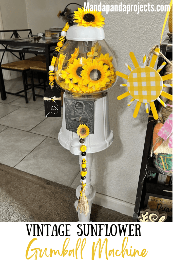 Sunflower Vintage Gumball Machine with sunflower heads inside and on top, and sunflower and bee mini wood bead garlands hanging form the top and coin turner. Gumball machine is painted all white.