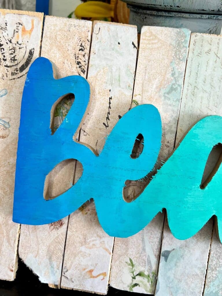 Up close of the letters B and E in the word Beach showing the blended paint transition from Dark blue to lighter blue to teal.