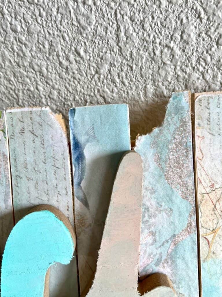 Wooden shims with the coastal beach printable mod podged to them with the ends broken and tattered to look as if it was weathered at the beach.