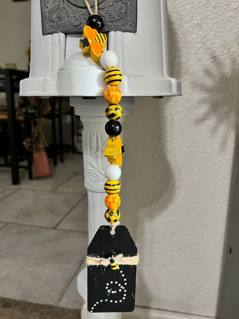 Mini bumblebee yellow and black wood bead garland hanging from the coin turner of the white vintage gumball machine.