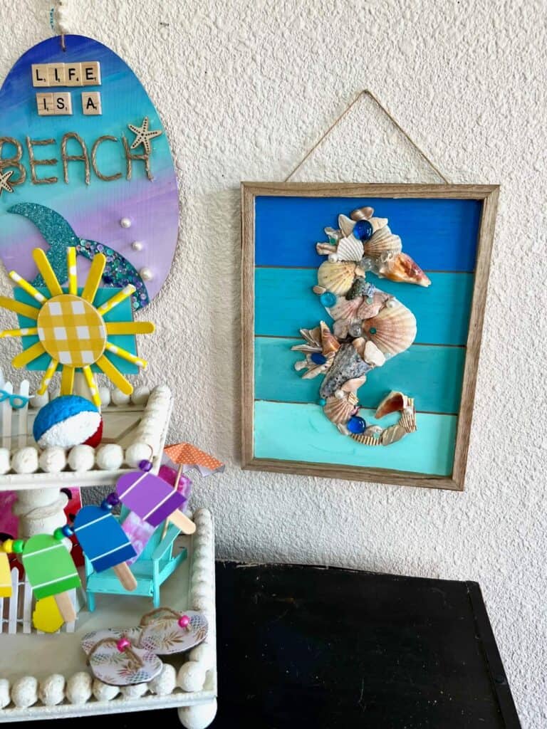 Seashell Seahorse hanging on the wall next to a mermaid tail craft and a summer theme tiered tray.
