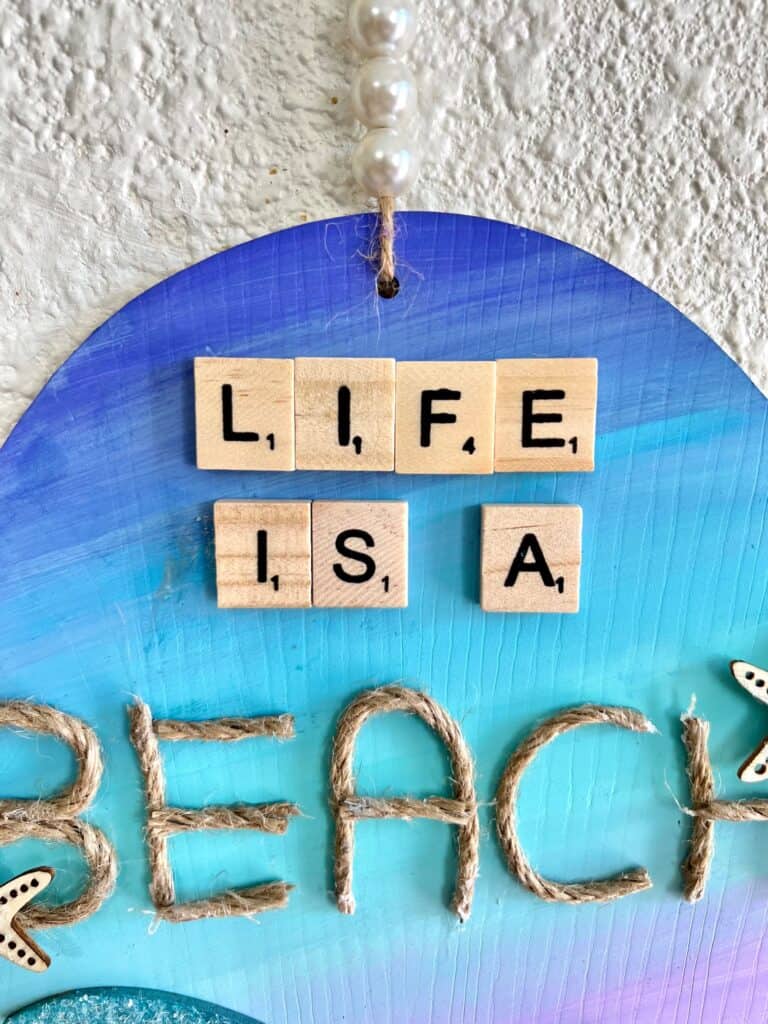 Scrabble letters that spell "Life is a" and then the word "Beach" spelled with jute twine letters.