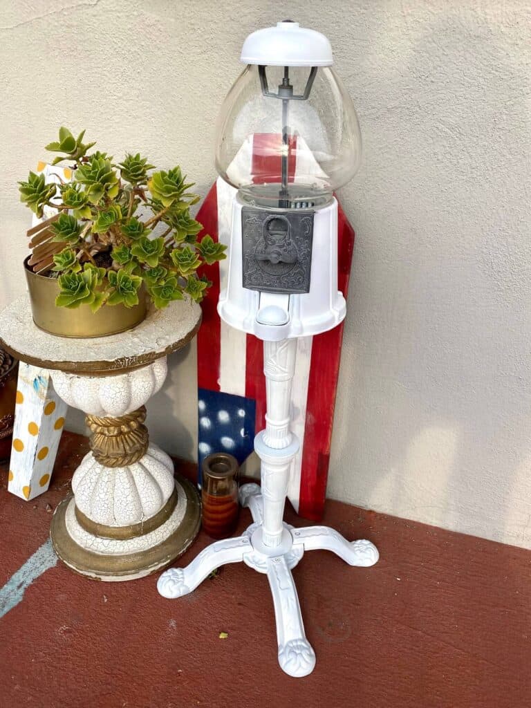 Vintage Thrift store flip. Gumball machine painted all white sitting on a front porch.