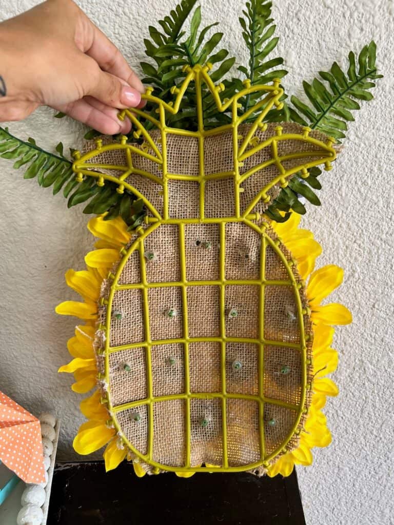 Back of the pineapple wreath form showing the sunflower stems pol=king through the burlap.
