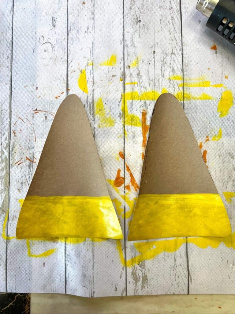 2 pieces of Kraft paper cut in triangles with the bottom widest strip painted yellow.