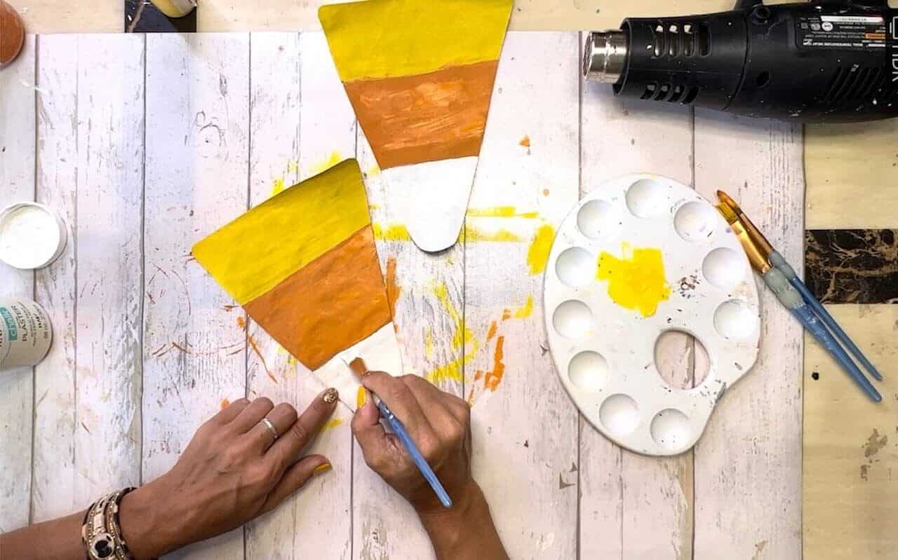 Paint the triangle shaped candy corn pieces of paper with Yellow paint at the bottom widest part, than orange, and white at the tip.