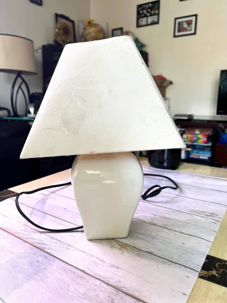White plain lamp with lampshade sitting on a table.
