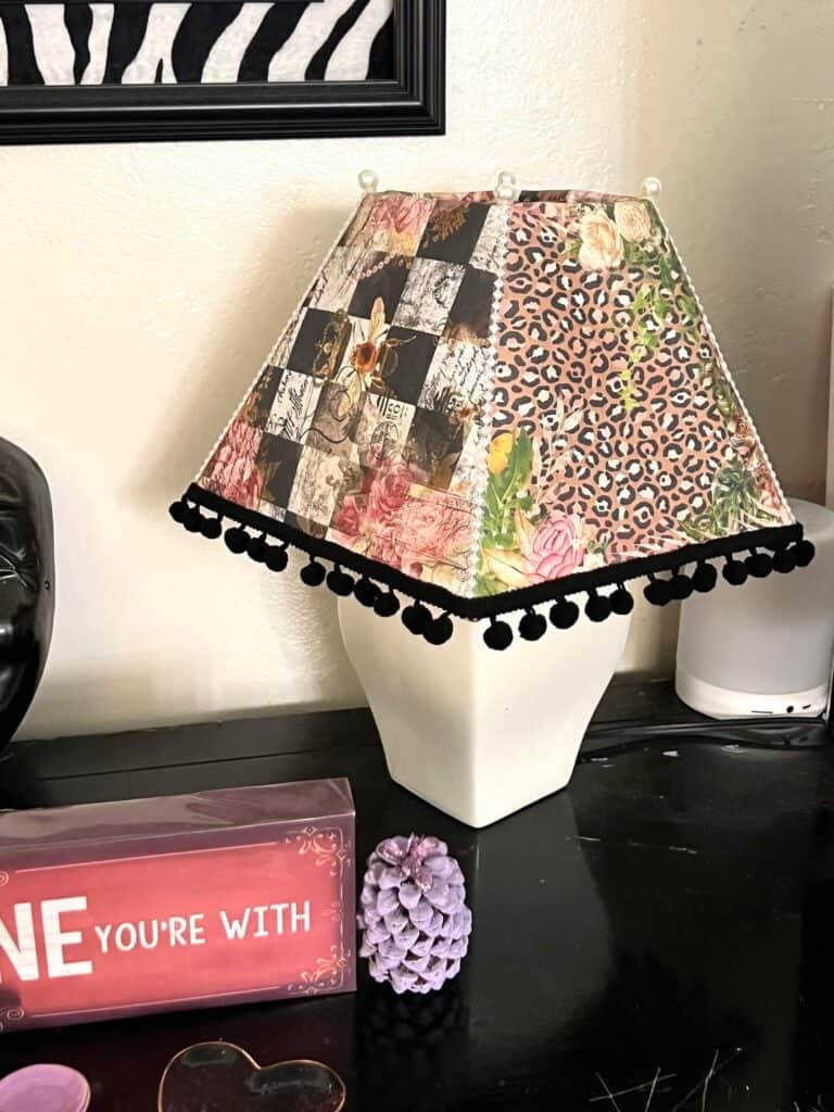 Thrift Store Lamp Flip. Makeover of a white lampshade with rice paper printables decoupaged onto the shade with black pom pom trim around the bottom and pearl strips up the side with pearl beads.
