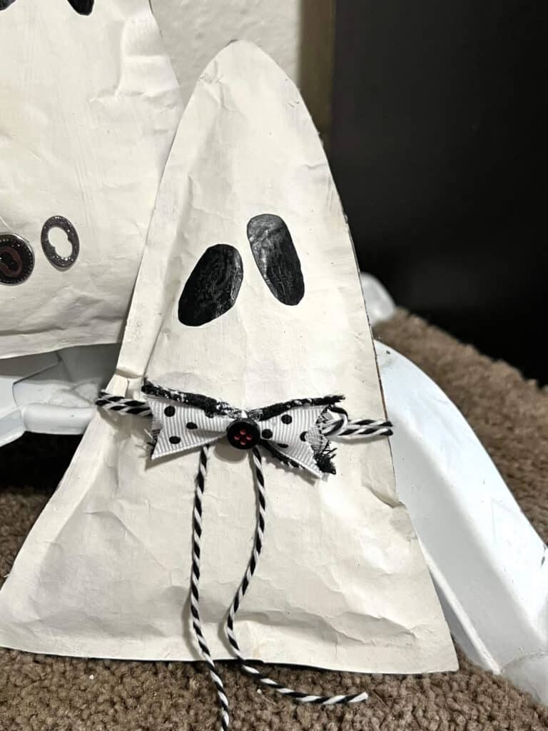 Boy kraft paper  ghost with black and white bakers twine and bow-tie and 2 wonky black oval eyes.