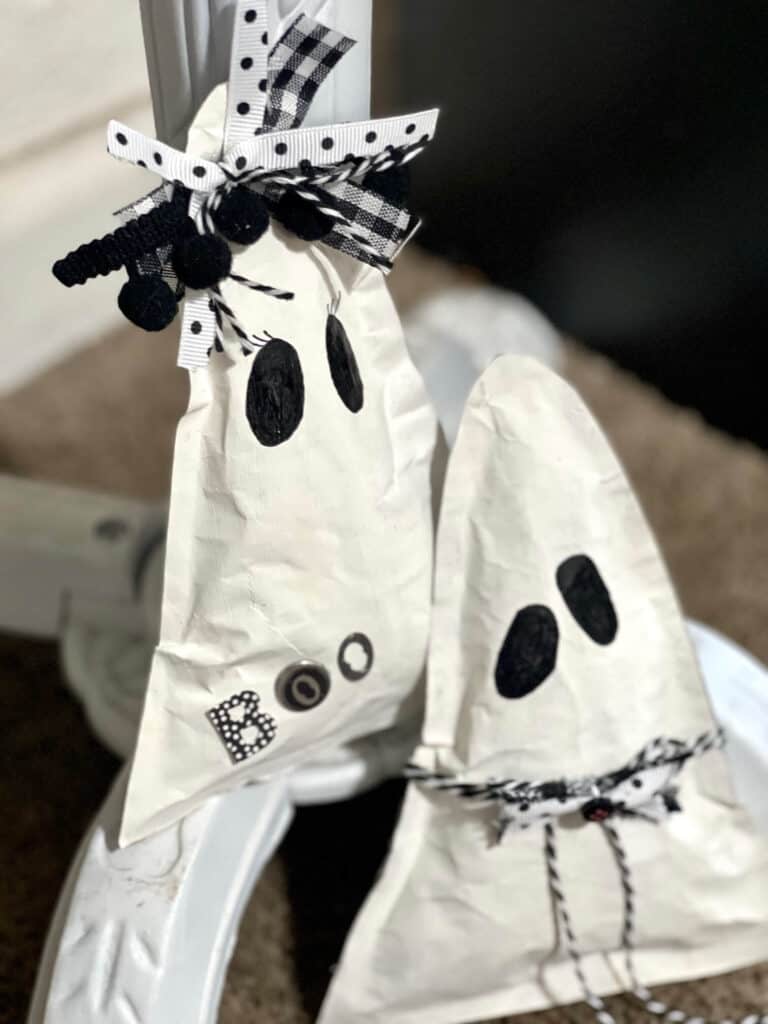 Kraft Paper Ghosts DIY easy and affordable Halloween decor. Boy and girl triangle shaped ghosts with black and white bow and bow tie and the word BOO, with 2 black eyes and no mouth.