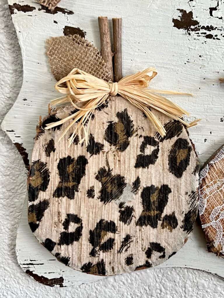 Leopard pumpkin wooden round with a small raffia bow.