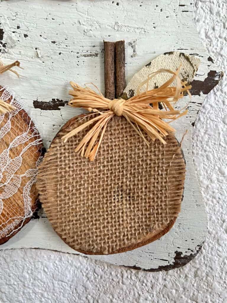 Burlap pumpkin wooden round with a small raffia bow.