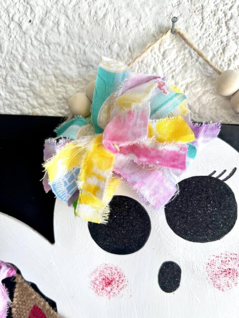Rainbow messy bow with fabric on the top of the dollar tree ghosts head.
