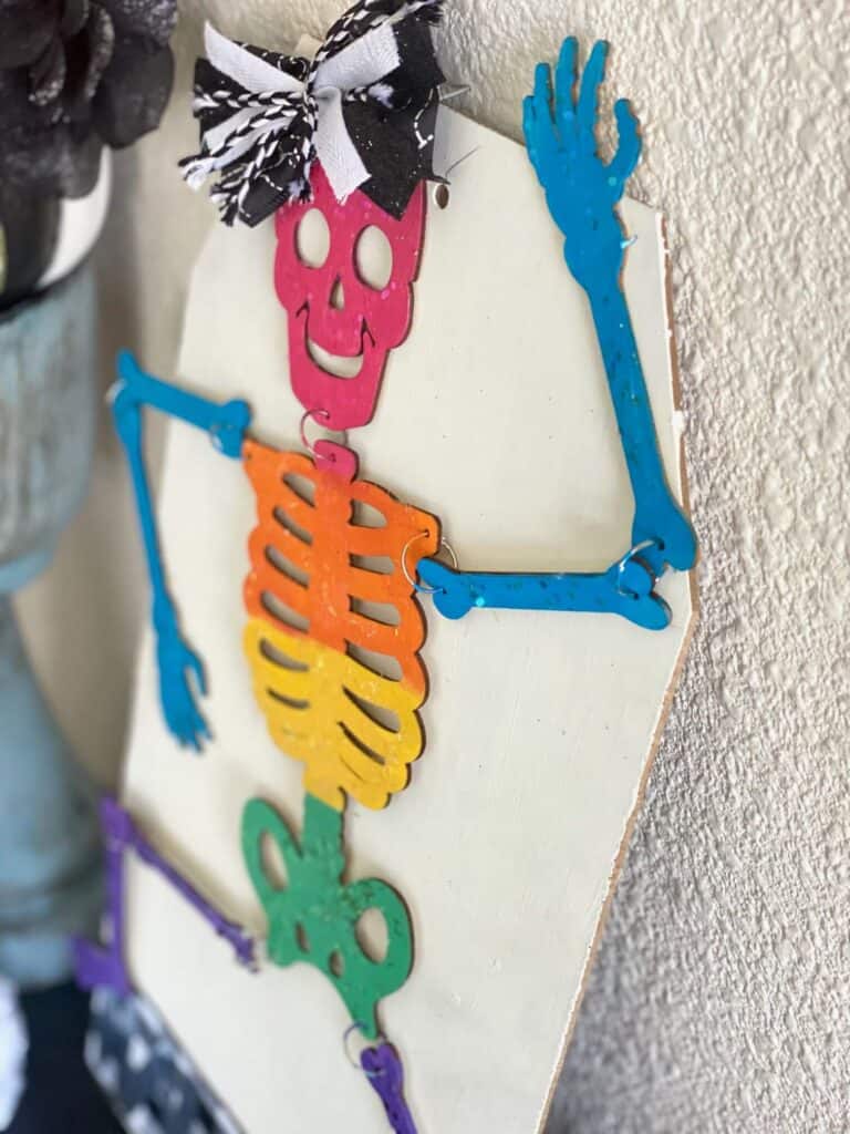 Closeup of the rainbow chunky glitter on the painted wooden skeleton.