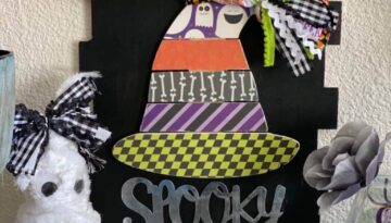 Dollar Tree Spooky Wood Pallet Witch Hat with traditional Halloween colored scrapbook paper, a messy bow at the top, on a black background sign.