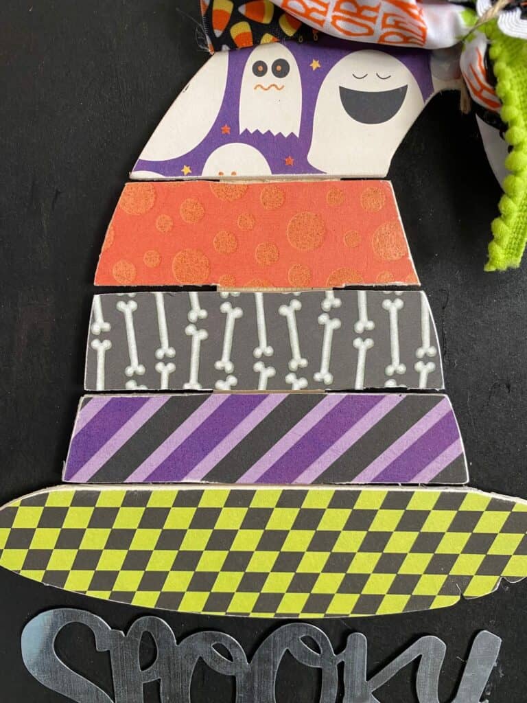 Close up of the traditional Halloween color and patterned scrapbook paper on the wooden slates of the witch hat.