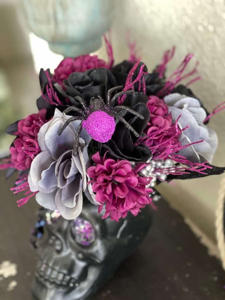 Black and purple glitter spider in the bouquet of grey, black, and purple flowers.