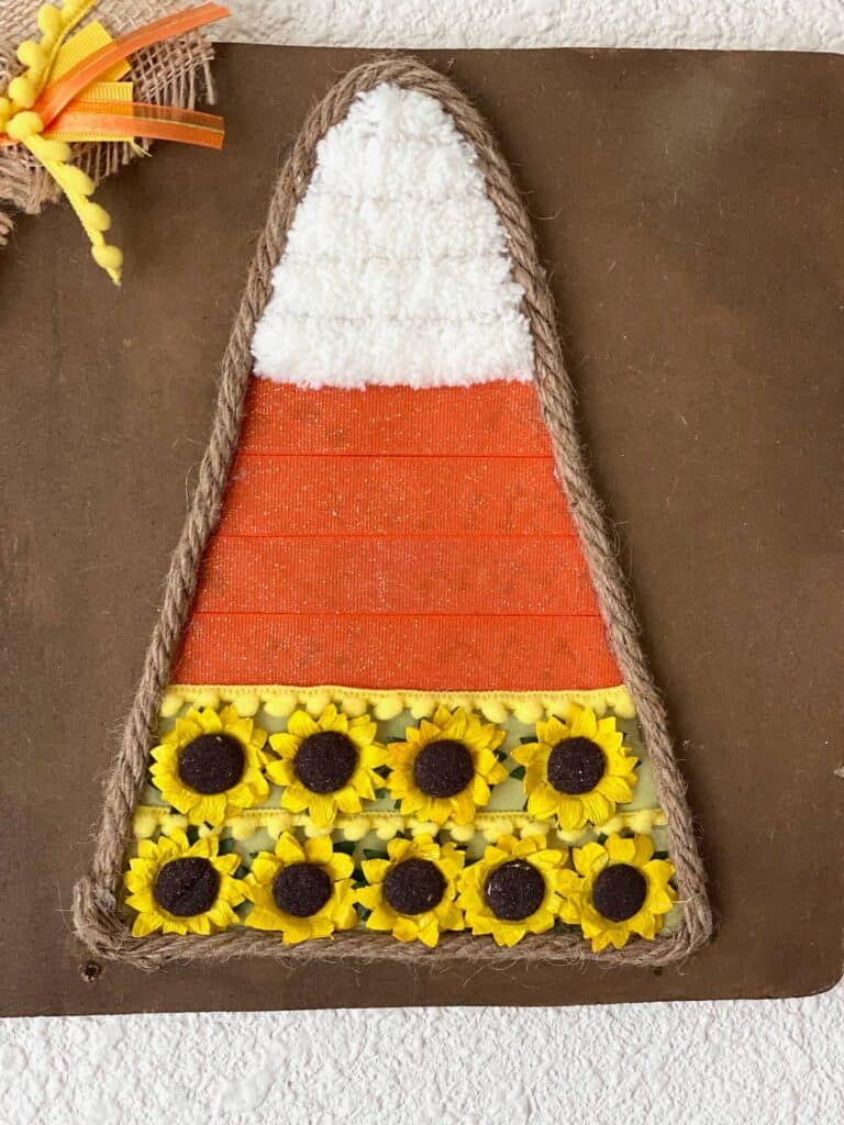 Close up of the center Candy Corn showing the orange ribbon, white yarn, and the sunflower heads, with jute rope around the edge.