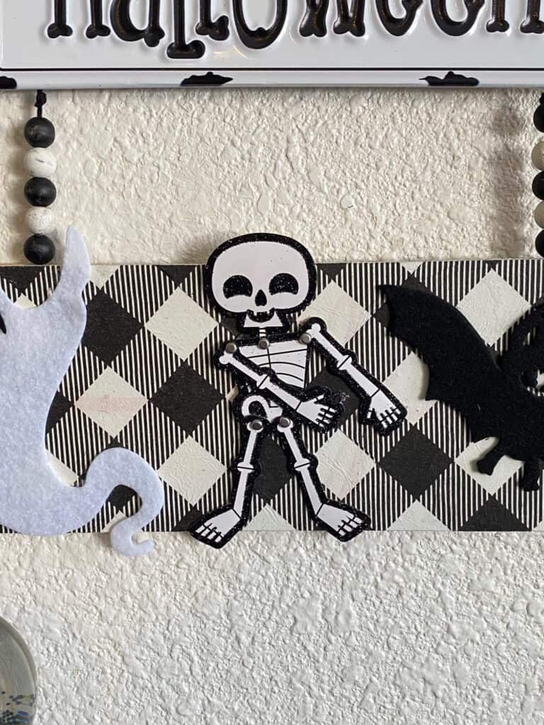 Close up of the paper skeleton that was pulled off of a Halloween card and is positioned doing "The Floss" dance.