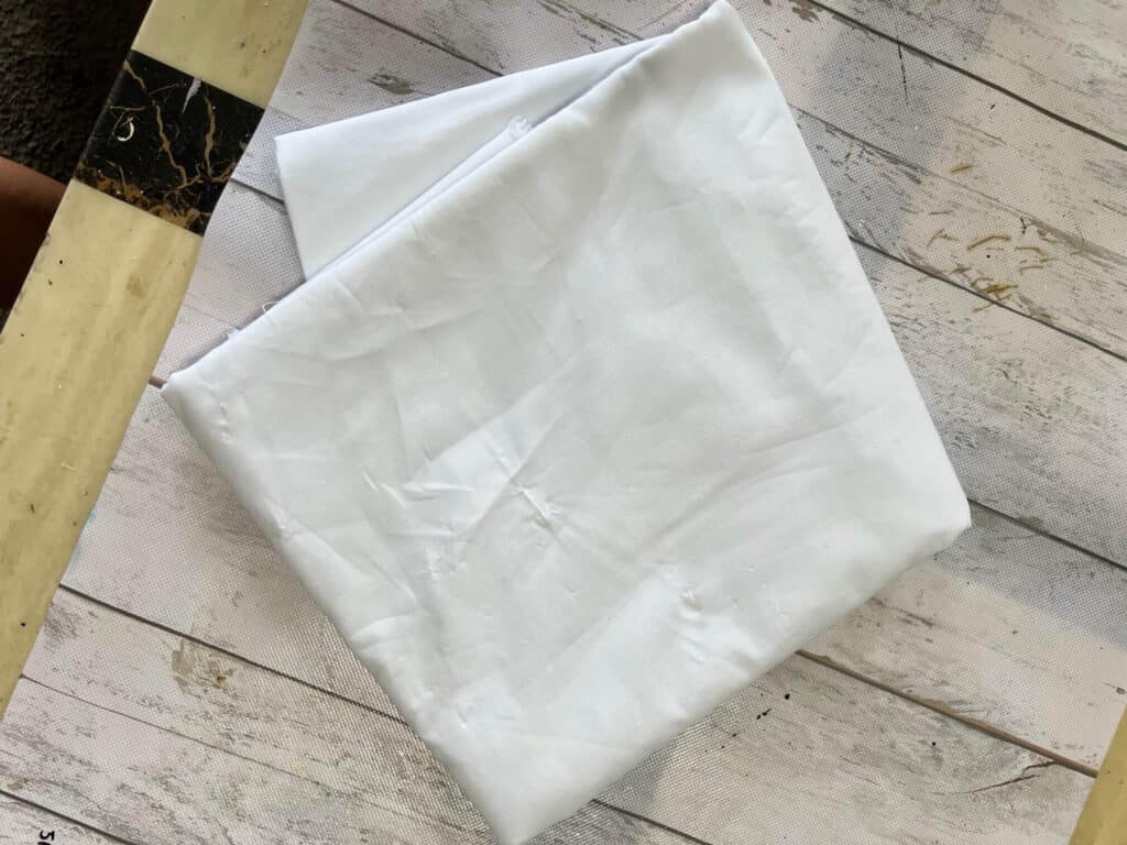 White muslin fabric folded on a table.
