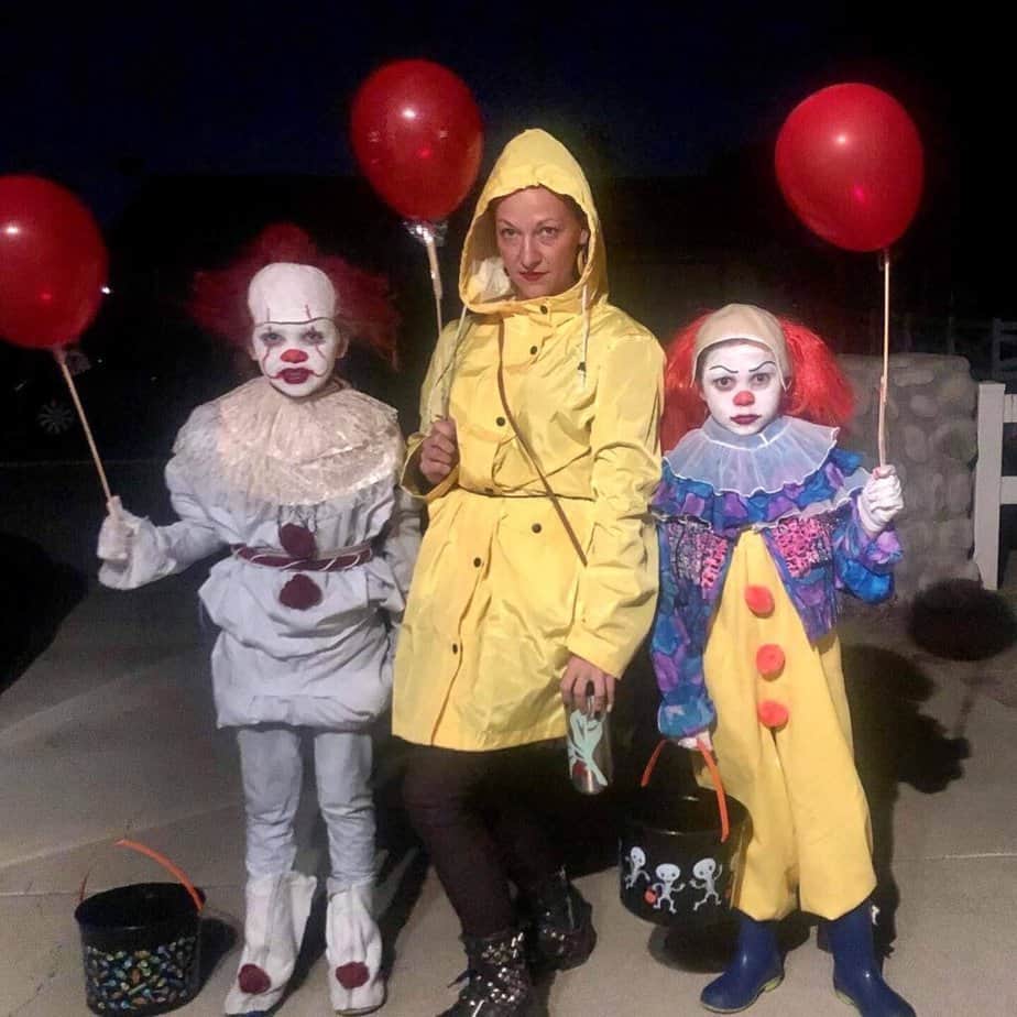 DIY Pennywise the Clown Halloween costumes with the original version of pennywise, the new movie version, and Georgie from the movie IT, all holding red balloons.