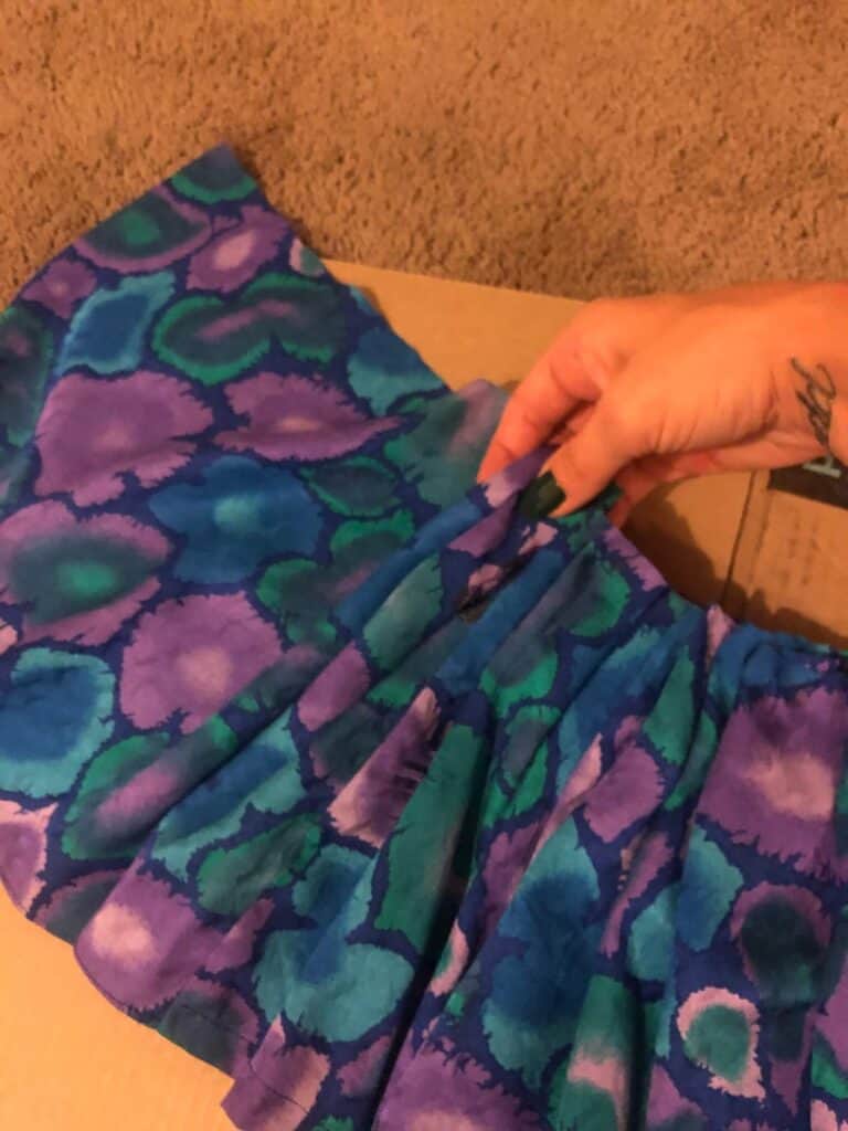 A piece of the purple, blue, and green fabric from the bottom of the dress that was cut off and ruffling it together to make a clown collar. 