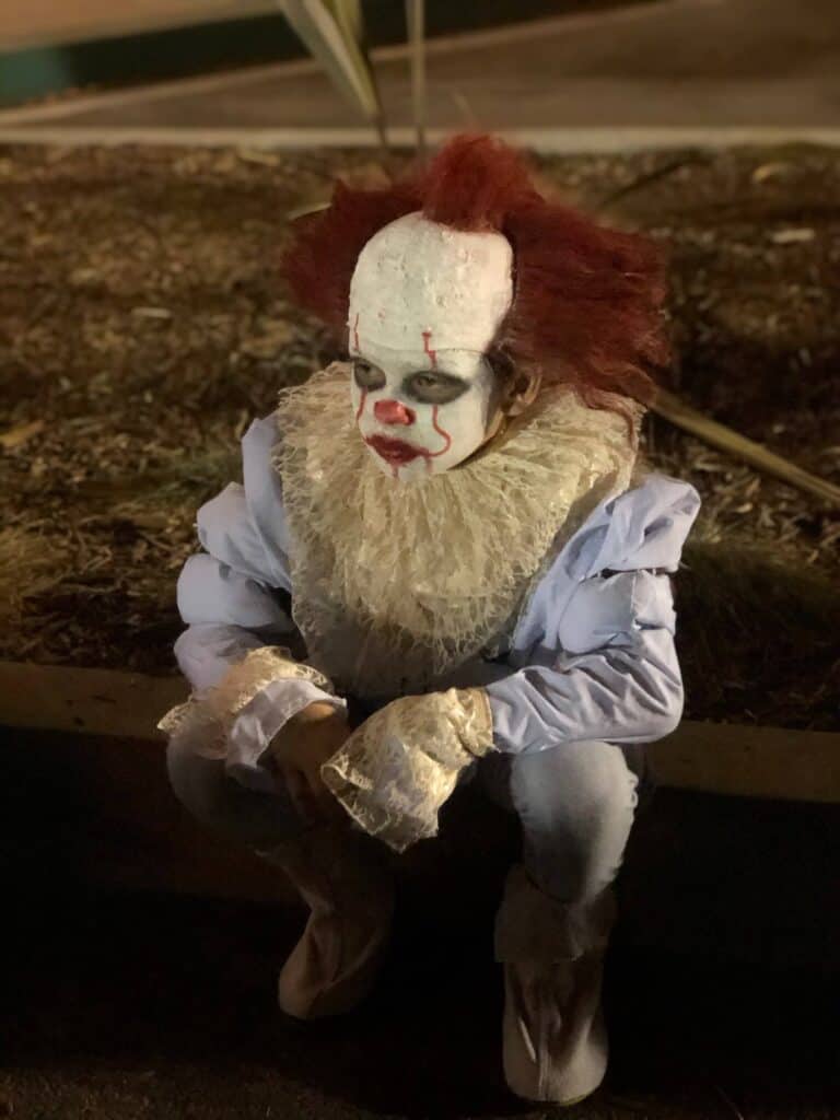 Maddox sitting on the curb staring off into the distance with the new Pennywise DIY Halloween costume on.