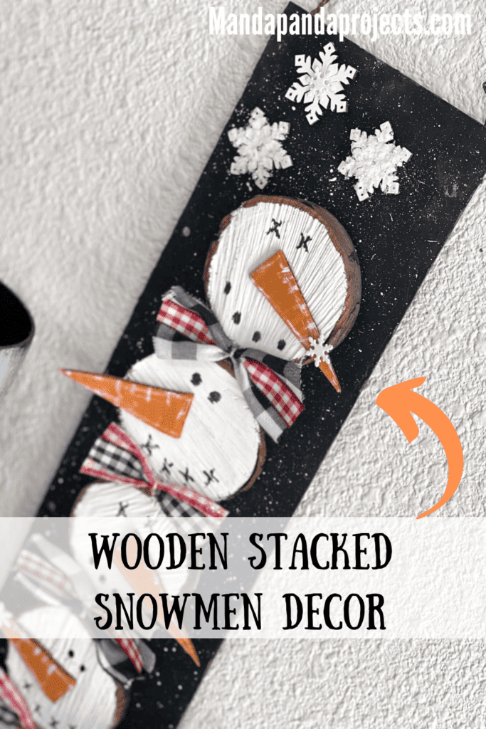 Wooden stacked snowmen decor made with wood round and 4 snowmen faces stacked on top of each other with bows in between on a black snowy background with a few snowflakes to decorate for winter.