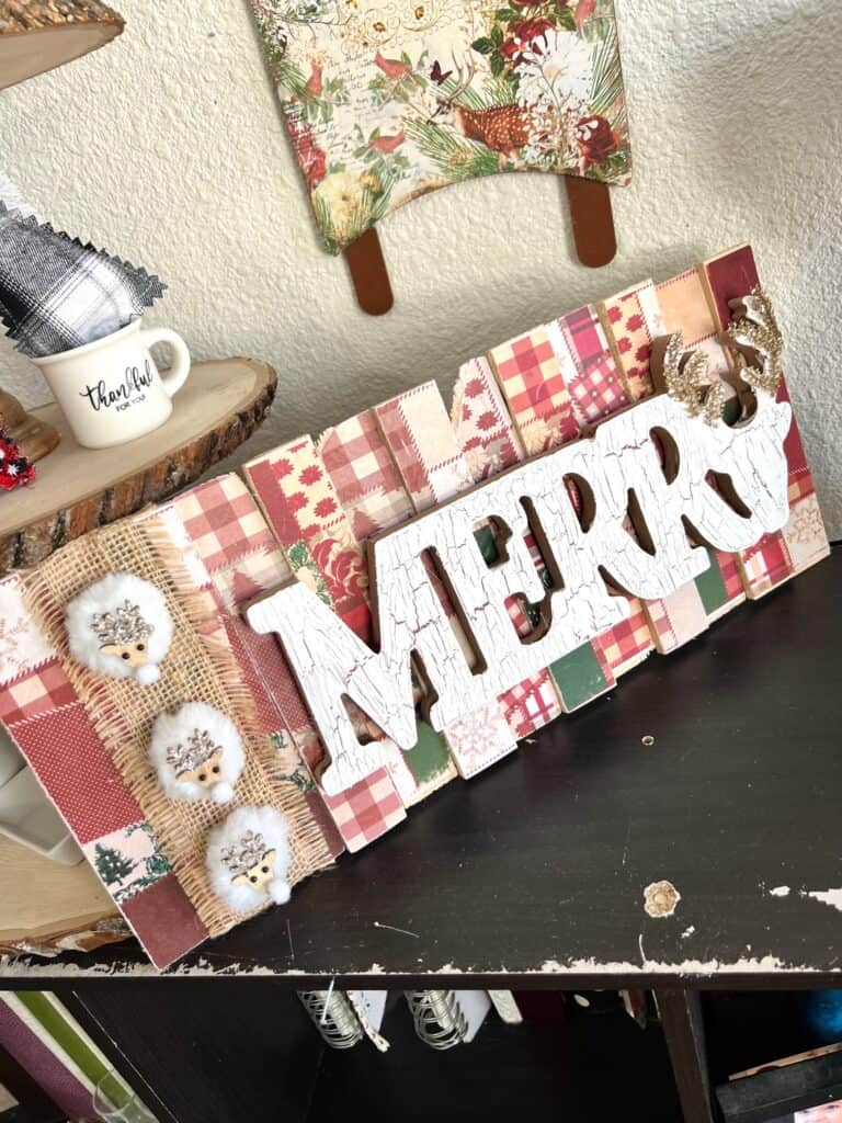 Dollar Tree Wooden Merry Sign made with a Christmas rice paper printable on wood shims with the crackle technique and mini white reindeer for DIY Christmas Decor.